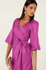A model wearing the Chateau Wrap Dress in colour Magenta (Pink), from the front, cropped image
