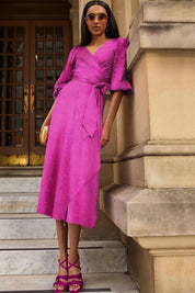 A model wearing the Chateau Wrap Dress in colour Magenta (Pink), from the front, showing the whole outfit