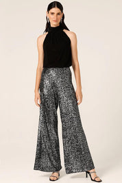A model wearing the Sequin Palazzo Pants in colour Blksilver (Black), from the front, showing the whole outfit