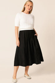A model wearing the Pleated Ain colourLine Skirt - Black (Black), from the front, showing the whole outfit