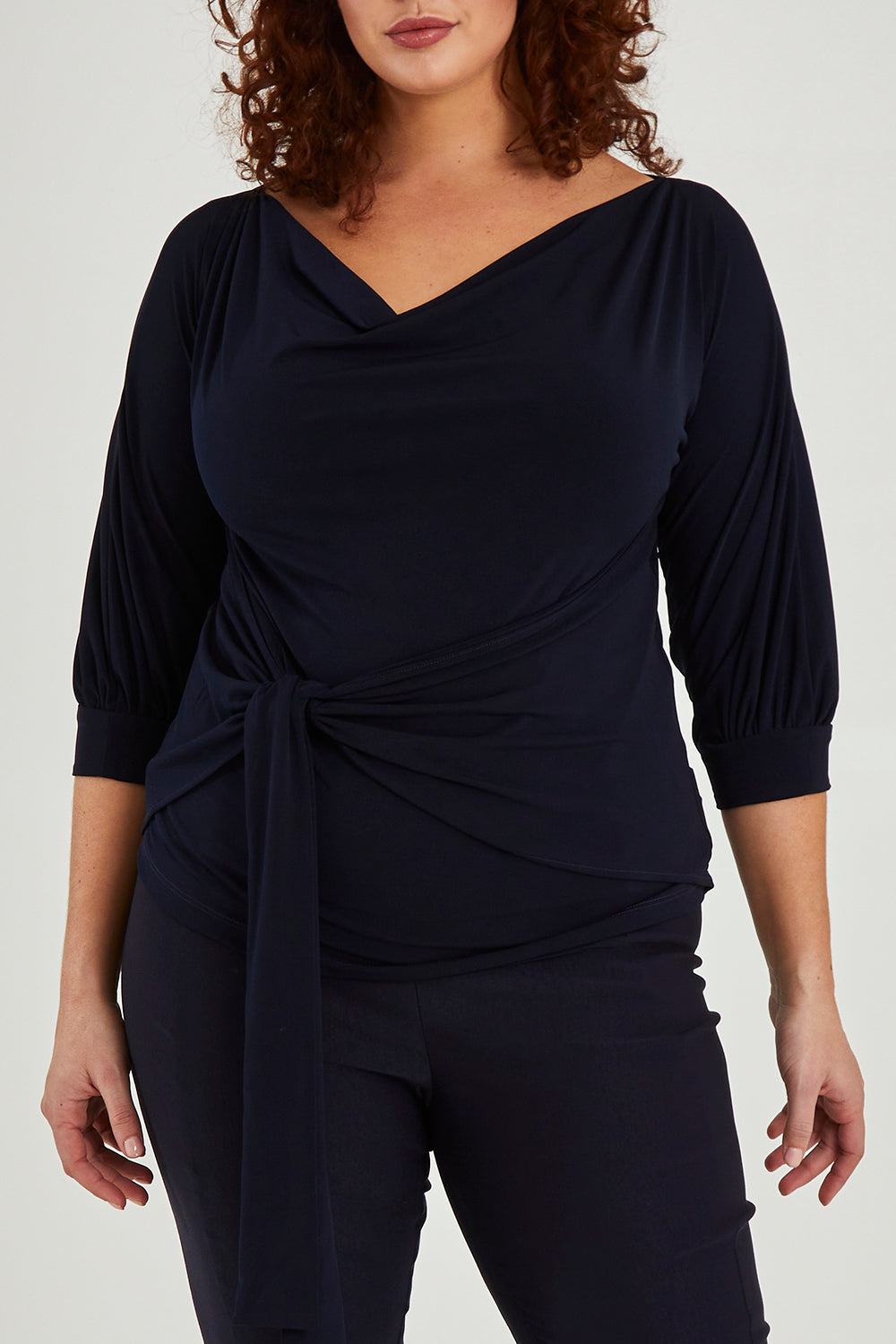 Model Maddy wearing size 16 of the Cowl Tie Top in colour Navy (Blue), from the front, cropped image