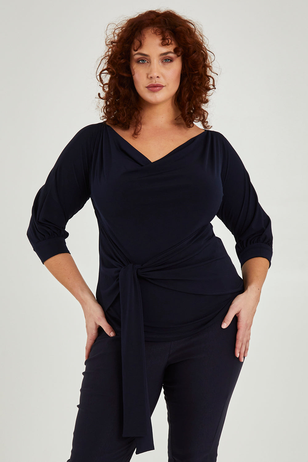 Model Maddy wearing size 16 of the Cowl Tie Top in colour Navy (Blue), from the front, cropped image
