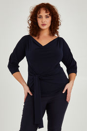 Model Maddy wearing size 16 of the Cowl Tie Top in colour Navy (Blue), from the front, cropped image