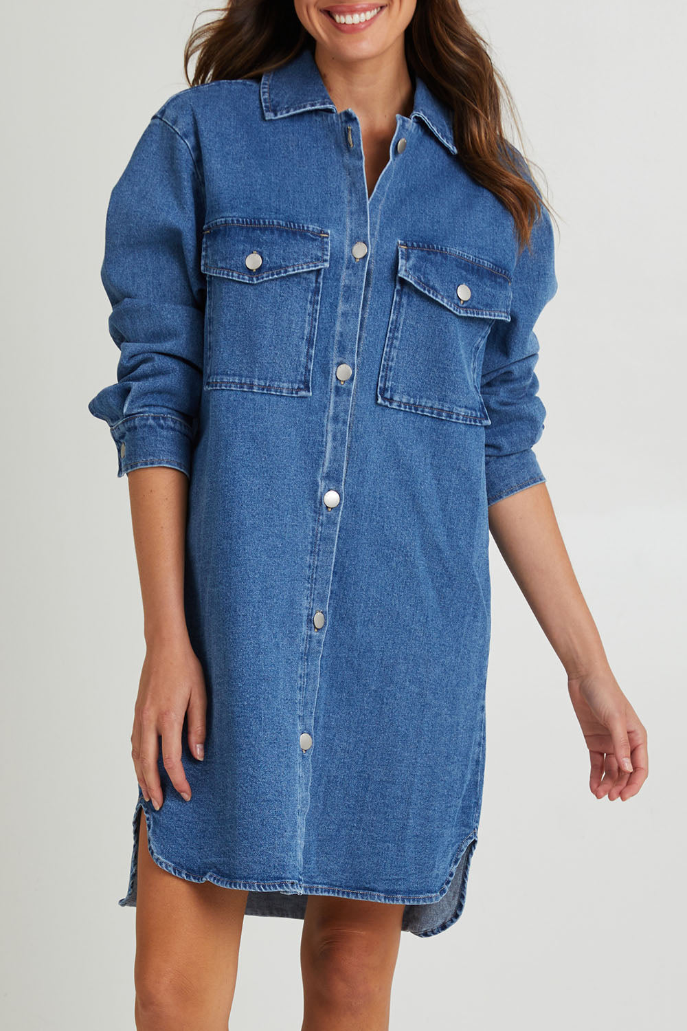 Model Madeline wearing size 10 of the Nya Long Denim Shacket Dress in colour 80Wash (Blue), from the front, cropped image