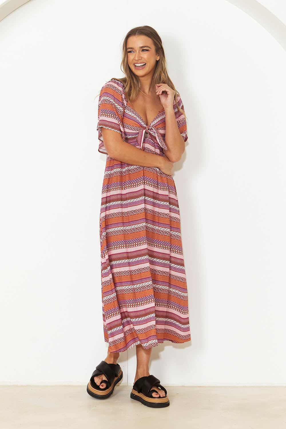 A model wearing the Raquel Midi Dress in colour Aztec (Pink), from the front, showing the whole outfit