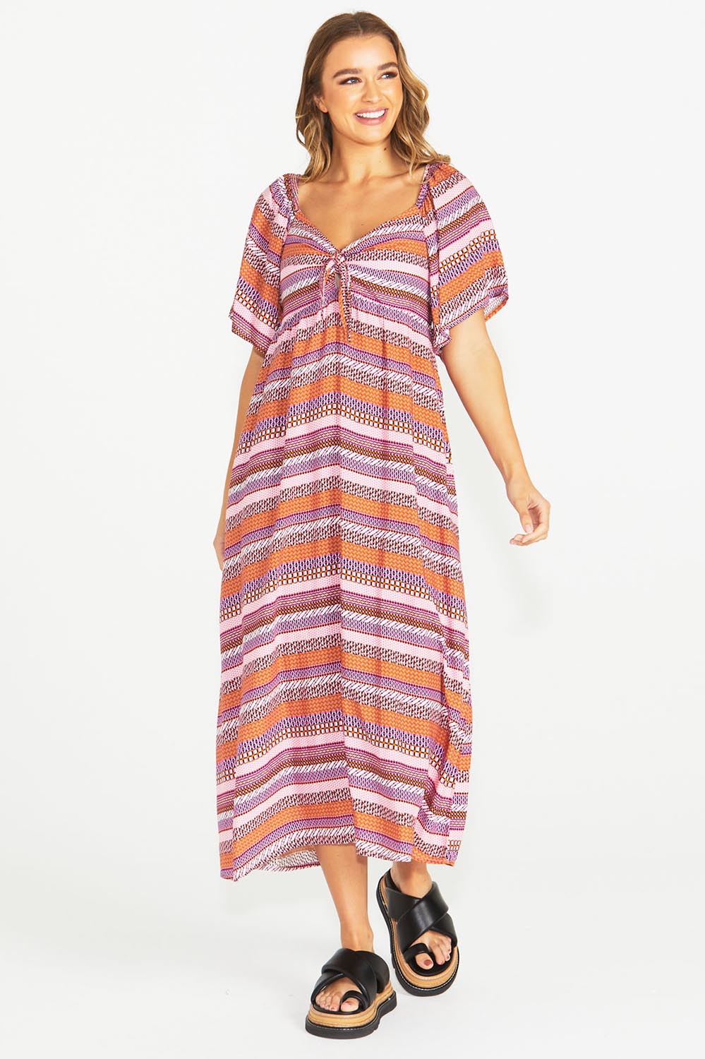 A model wearing the Raquel Midi Dress in colour Aztec (Pink), from the front, showing the whole outfit