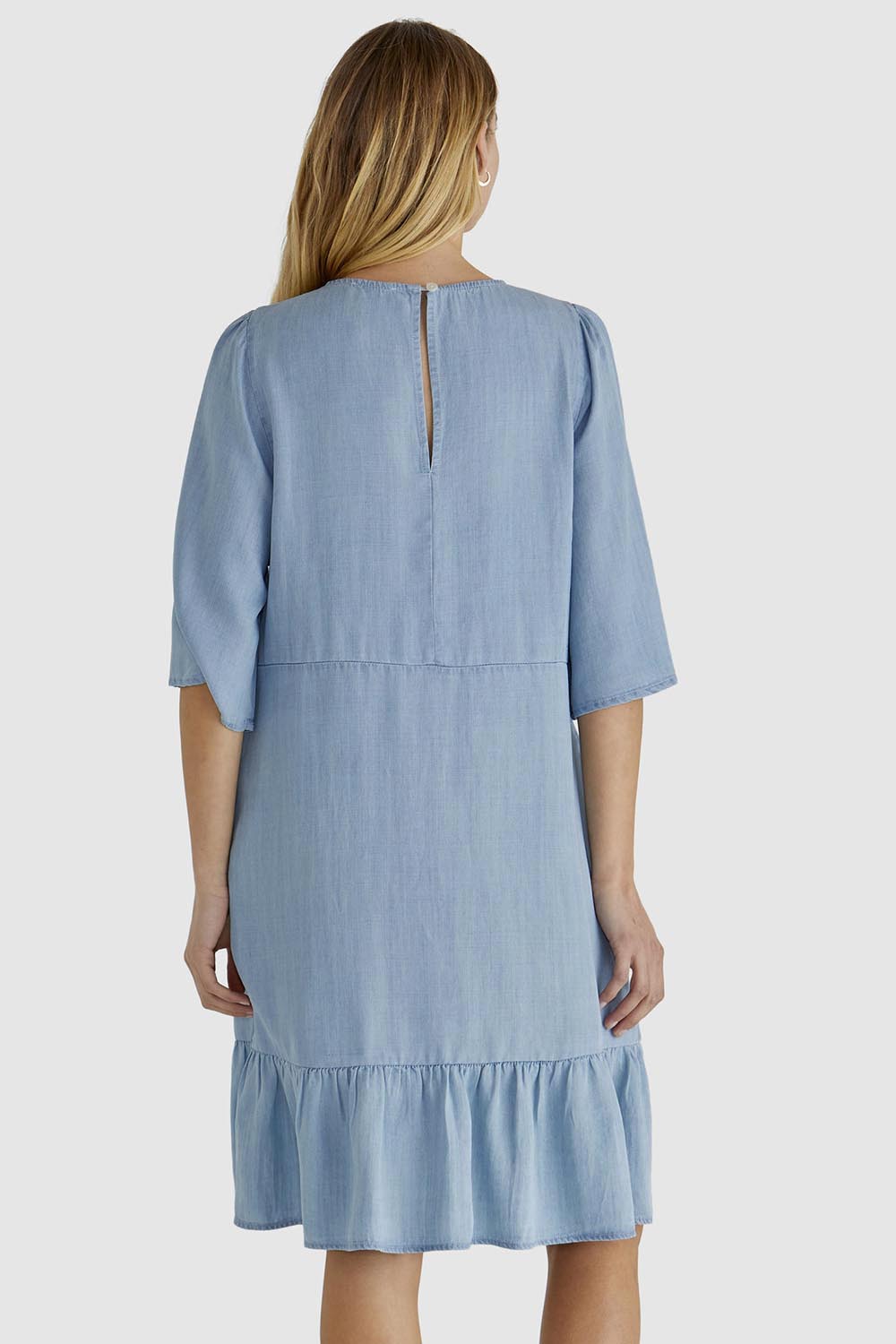 A model wearing the Rye Lyocell Dress in colour Chambray (Blue), from the back