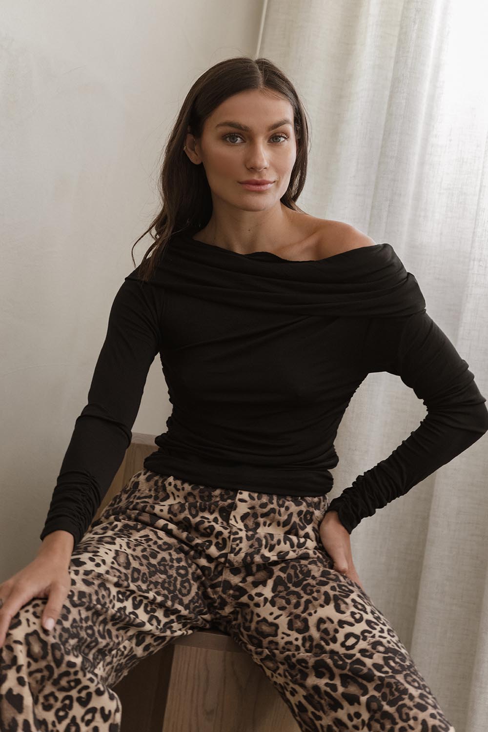 A model wearing the Caprice Top in colour Black (Black), from the front, showing the whole outfit