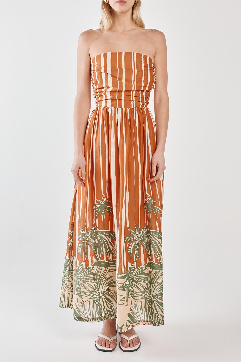 A model wearing the Mina Cotton Strapless Dress in colour Palmstripe, from the front, cropped image