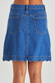 A model wearing the Vale Scalloped Denim Skirt in colour Midblue (Blue), from the back