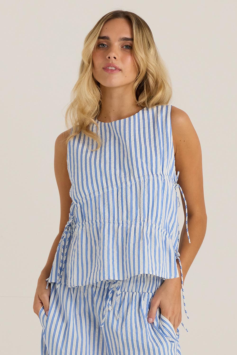A model wearing the Aziza Gathered Tie Top in colour Bluewhite (Blue), from the front, cropped image