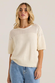 A model wearing the Cherri Top in colour Cream, from the front, cropped image