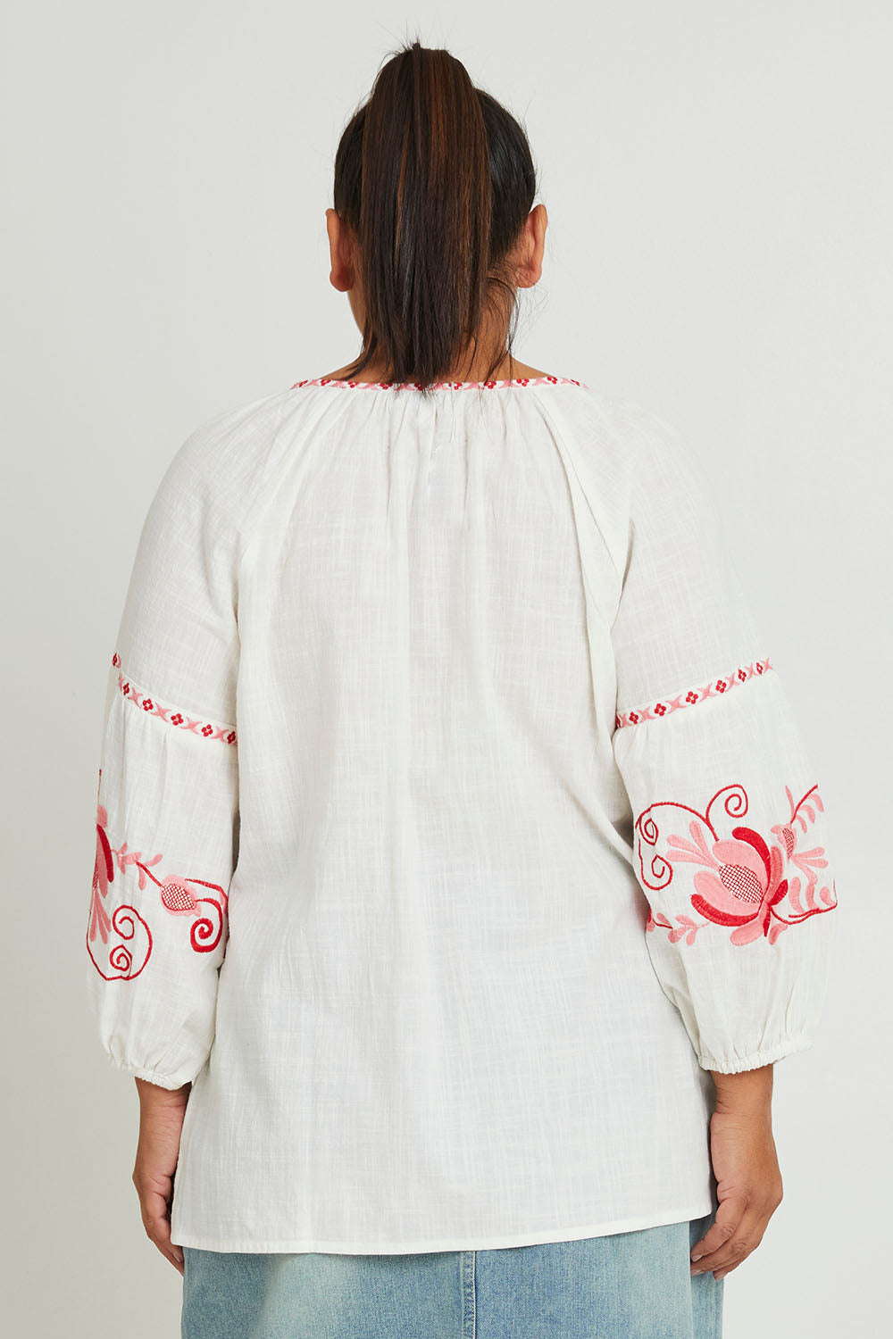 Model Ashleigh wearing size 16 of the Whitehaven Beach Cotton Blouse in colour Whitepink (White), from the back