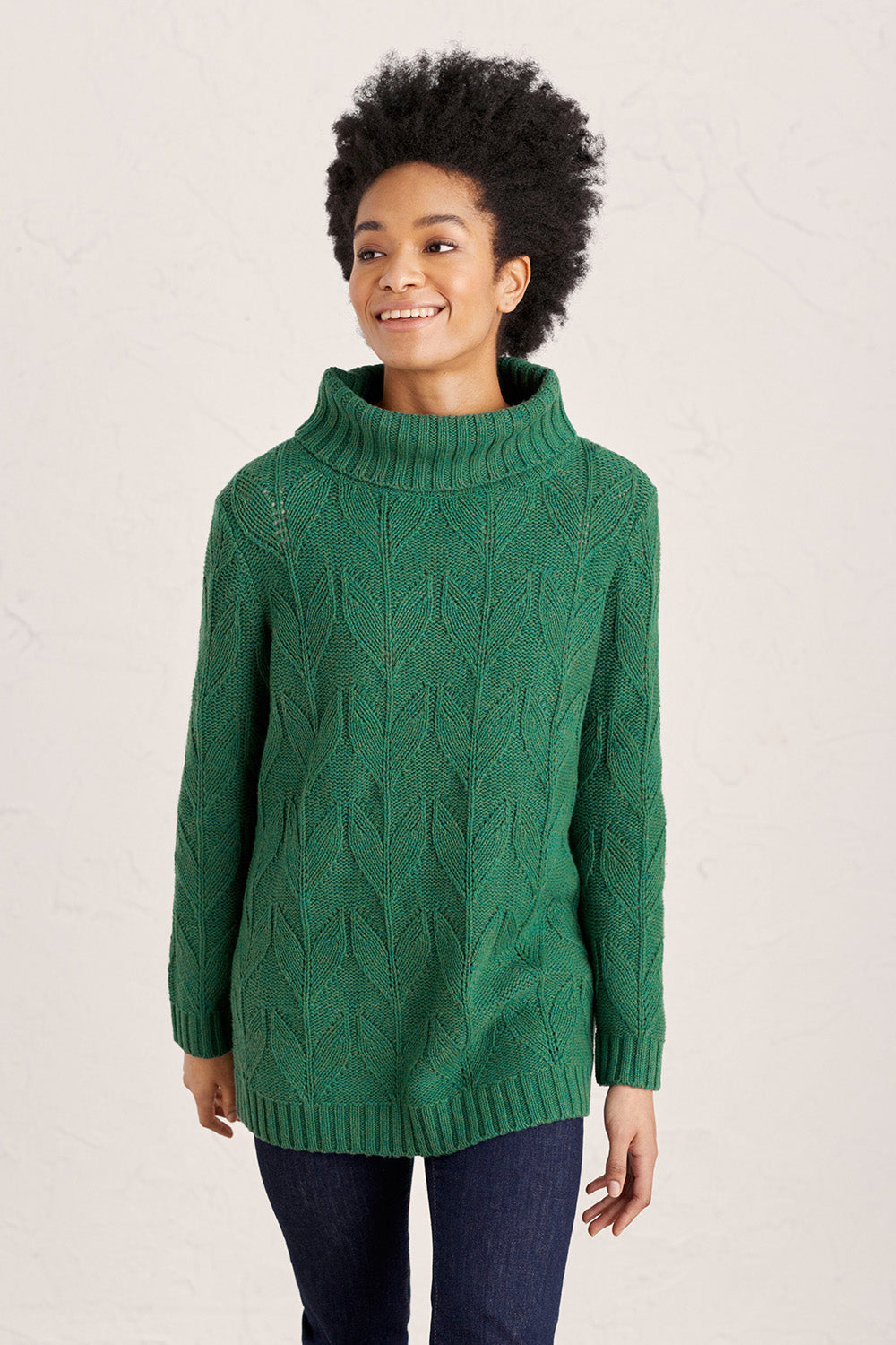 A model wearing the Coast Road Jumper in colour Evergreen (Green), from the front, cropped image