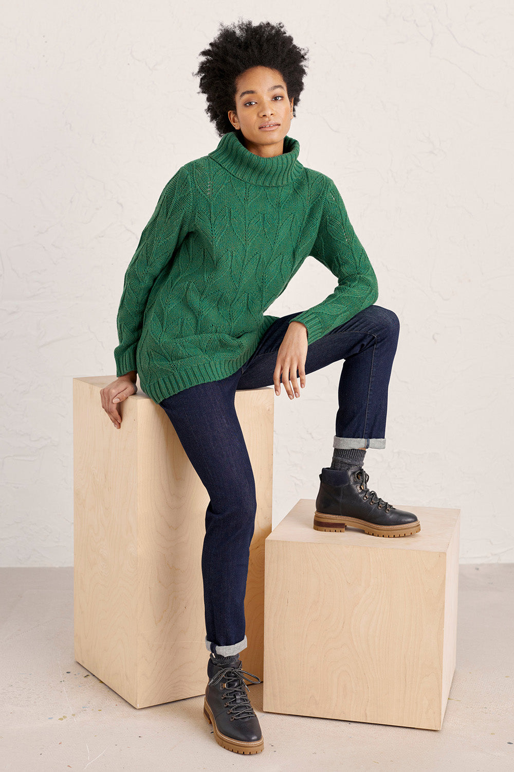 A model wearing the Coast Road Jumper in colour Evergreen (Green), from the front, showing the whole outfit