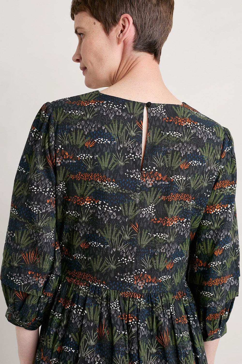 A model wearing the Sea Line Dress in colour Moormeadow (Black), from the back
