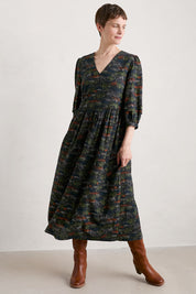 A model wearing the Sea Line Dress in colour Moormeadow (Black), from the front, showing the whole outfit