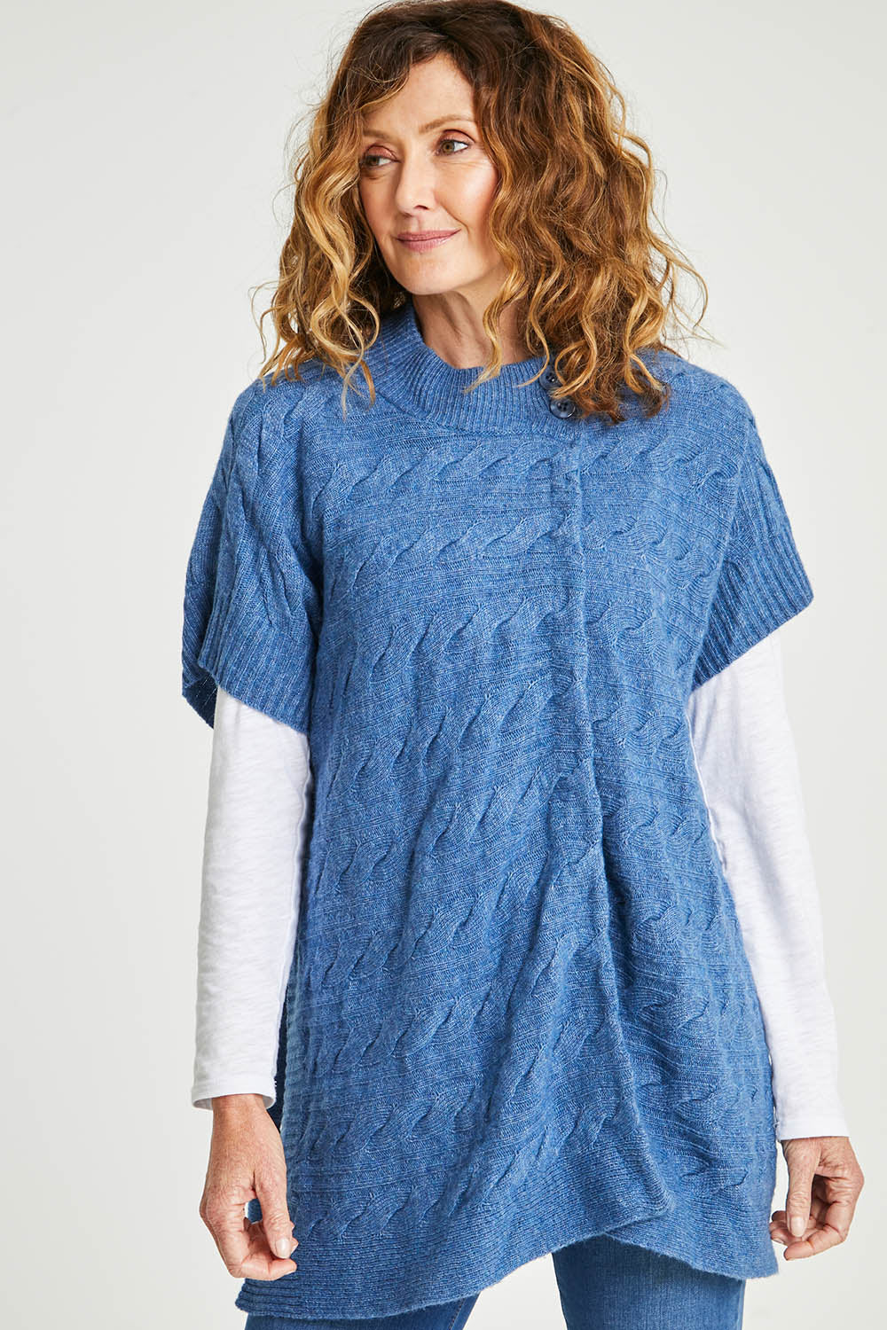 Model Emma wearing size S of the Lambswool Blend Cable Poncho in colour Denim (Blue), from the front, cropped image