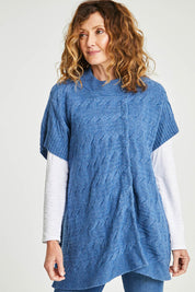Model Emma wearing size S of the Lambswool Blend Cable Poncho in colour Denim (Blue), from the front, cropped image