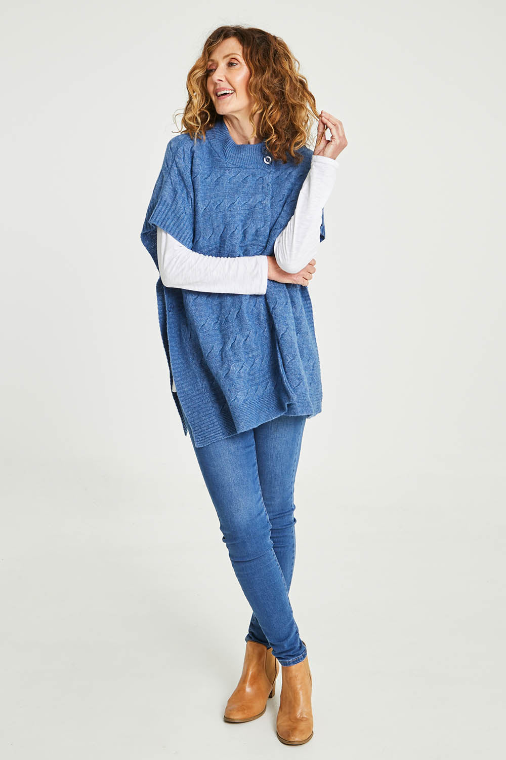 Model Emma wearing size S of the Lambswool Blend Cable Poncho in colour Denim (Blue), from the front, showing the whole outfit