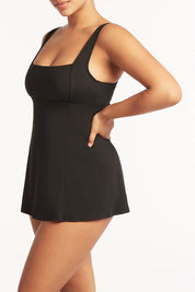 A model wearing the Square Neck Tummy Control Swim Dress in colour Black (Black), from the front, cropped image
