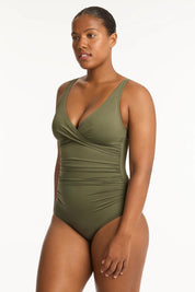 A model wearing the Eco Essentials Cross Front One Piece in colour Khaki (Green), from the front, cropped image