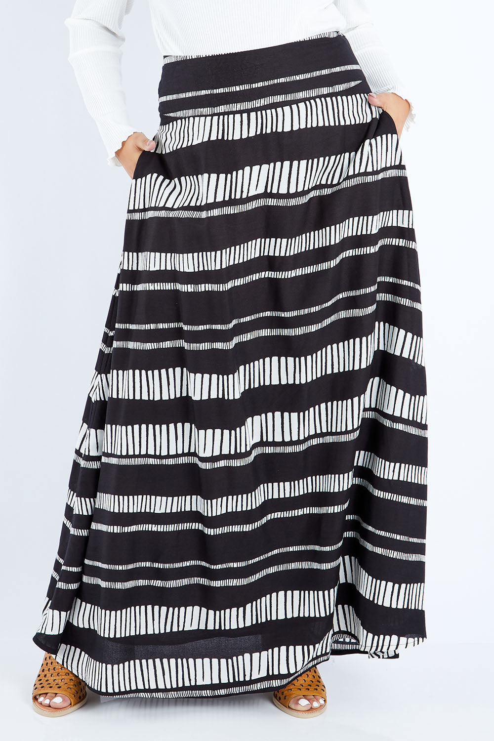 Model Sasha-Lee wearing size 16 of the Rosie Maxi Skirt in colour Sandstone (Black), from the front, cropped image