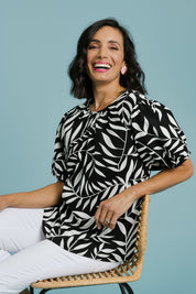 Model Natalie wearing size 10 of the Rachel Bell Sleeve Top in colour Vines (Black), from the front, showing the whole outfit