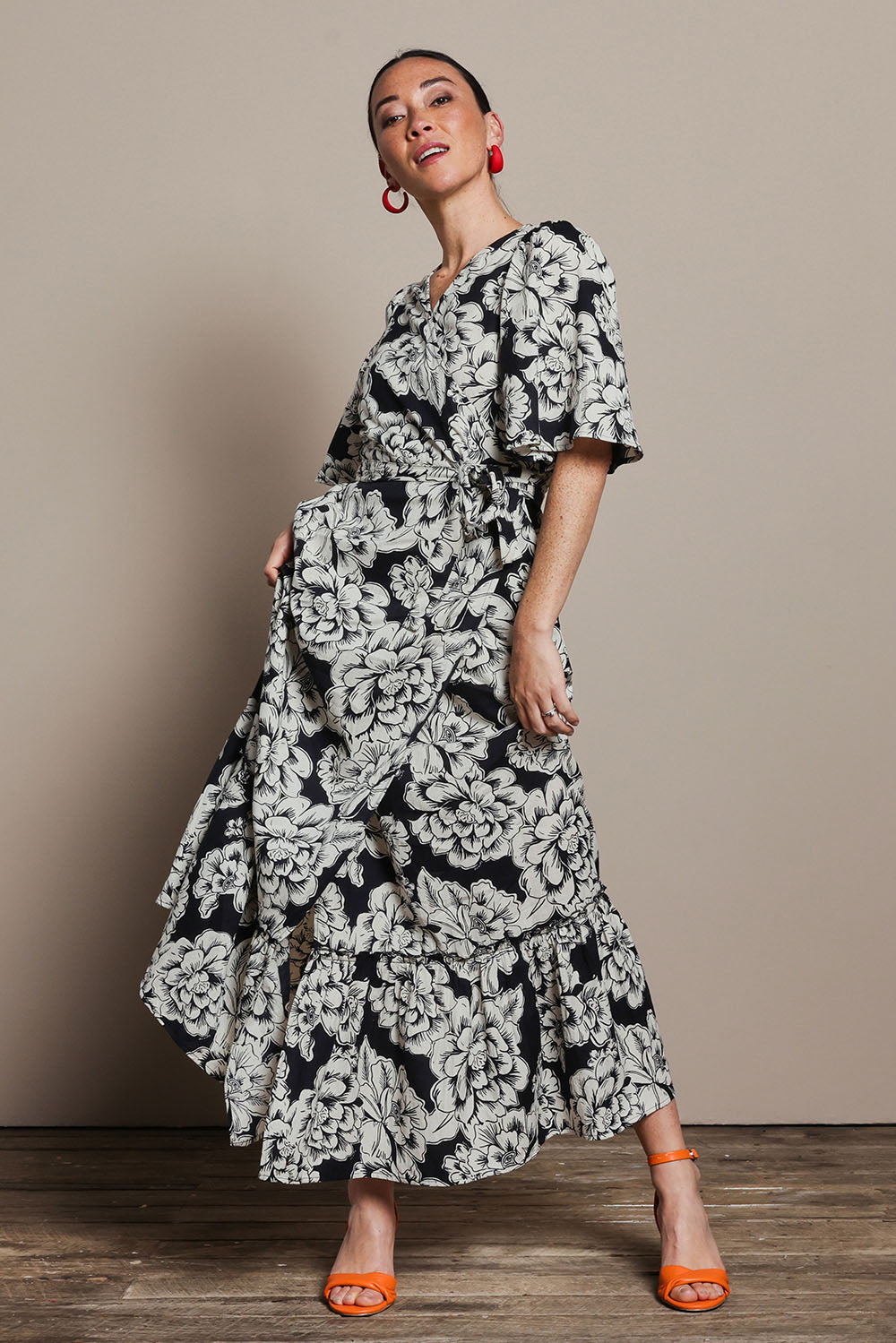 Model Katie wearing size 10 of the Anastasia Cotton Wrap Dress in colour Blooming (Black), from the front, showing the whole outfit