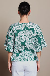 Model Tahnee wearing size 10 of the Kylie Frill Sleeve Cotton Top in colour Blooming (Green), from the back