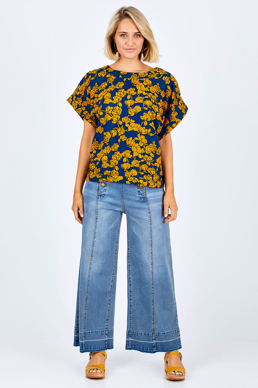 Model Emma wearing size 10 of the Lola Bell Sleeve Top Entangled Vines in colour Gold, from the front, showing the whole outfit