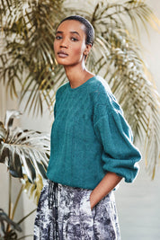 A model wearing the Bennedetta Pointelle Jumper in colour Malgreen (Green), from the front, showing the whole outfit