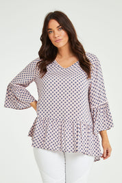 Model Laura wearing size L of the Ruffle Hem Spot Top in colour Pink (Pink), from the front, cropped image