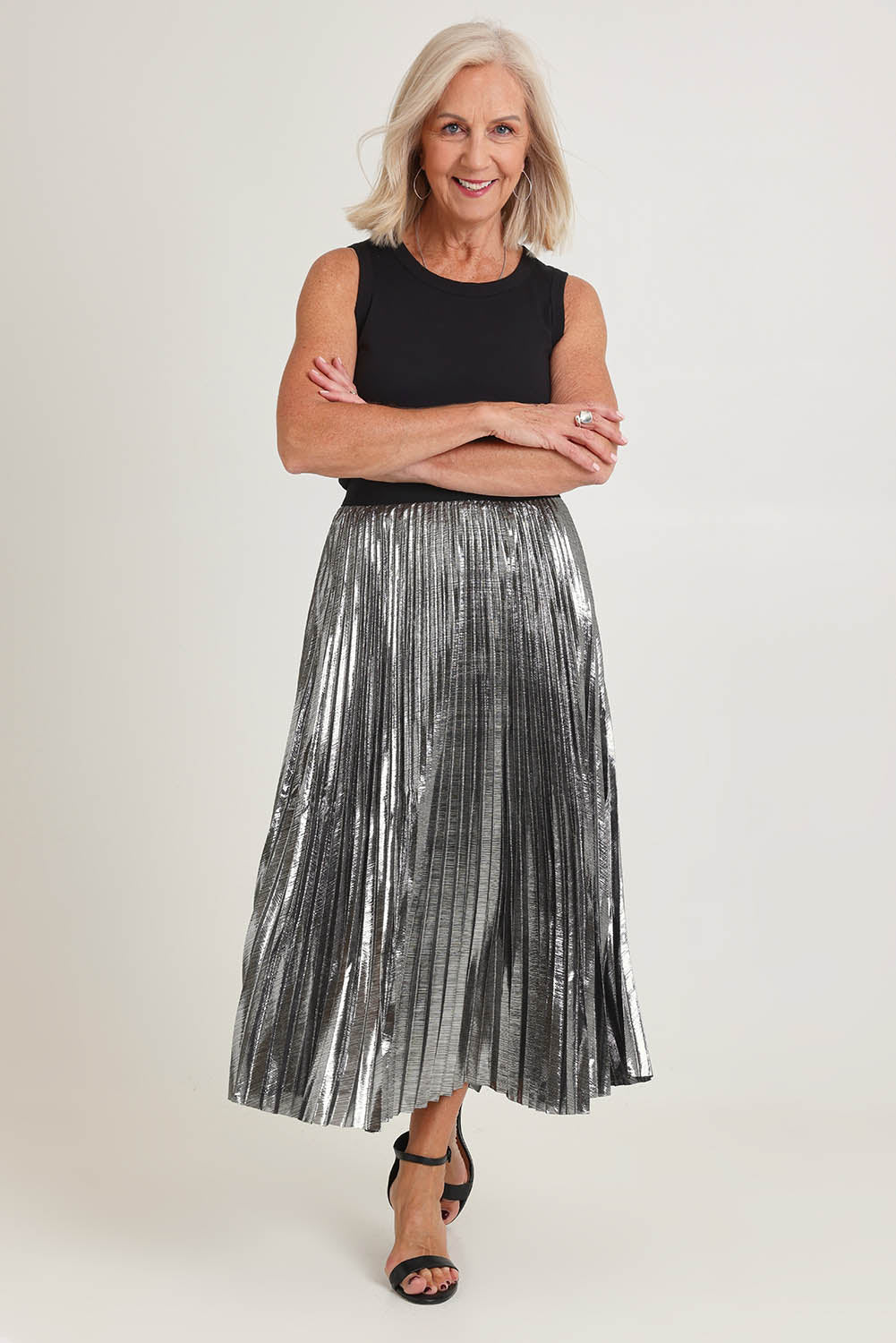 Model Sandy wearing size S of the Shimmer Pleated Skirt in colour Silver (Metallics), from the front, showing the whole outfit