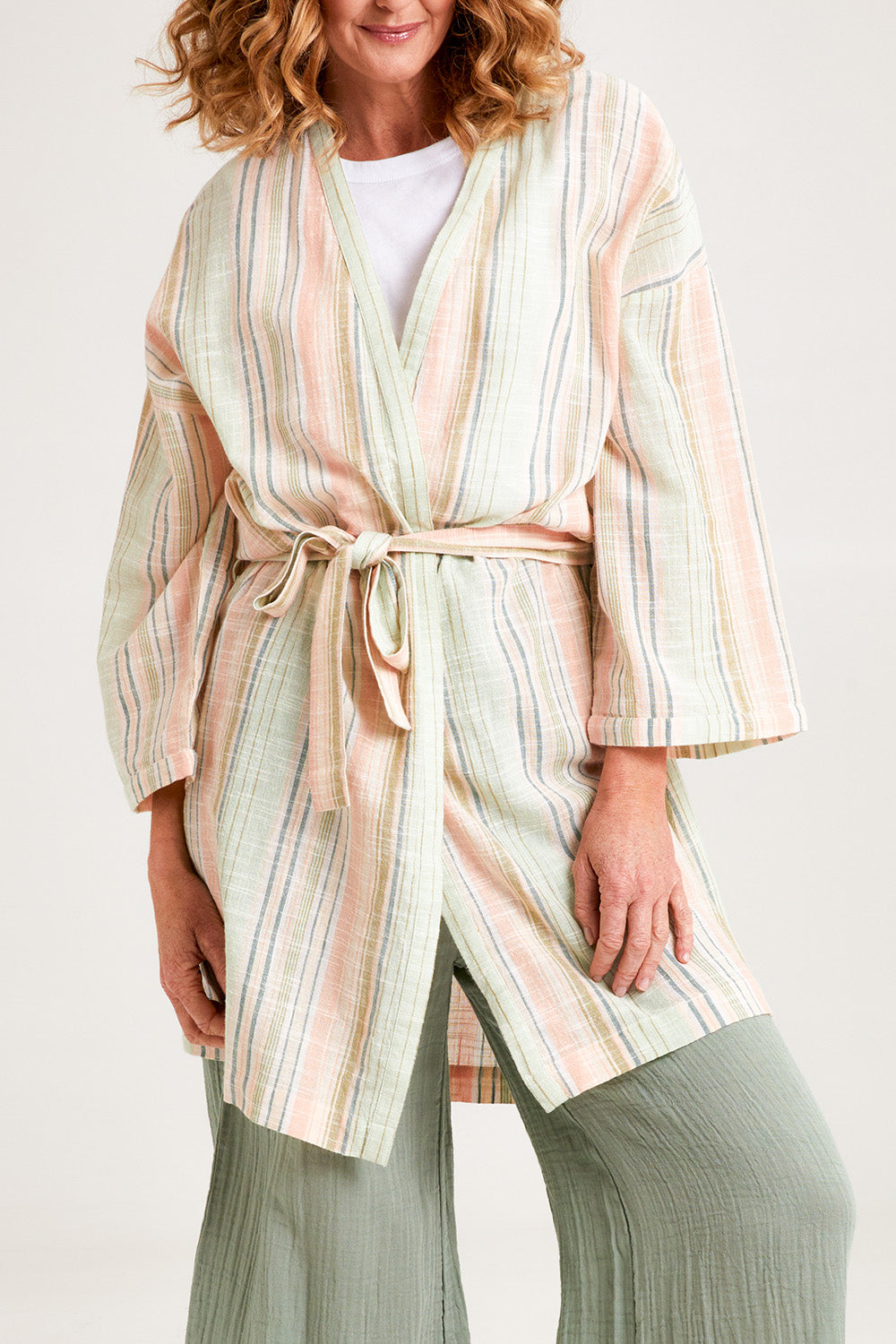 Model Emma wearing the Cotton Stripe Dressing Robe in colour Softstripe (Green), from the front, cropped image