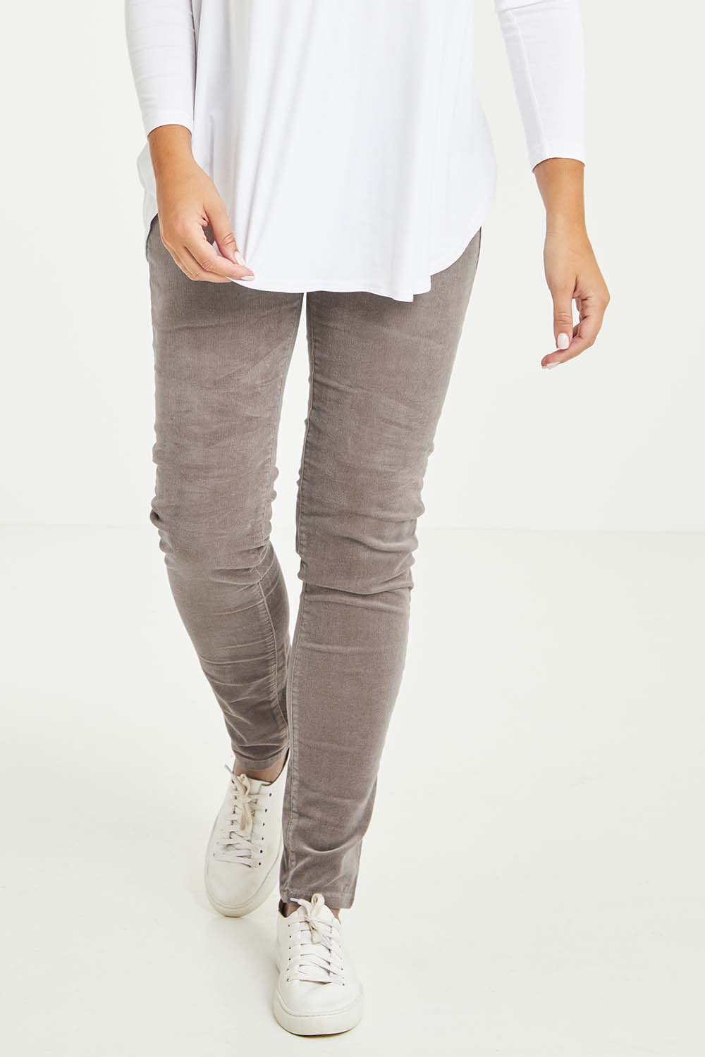 Model Tahlia wearing size 10 of the Skinny Leg Cord Pull On Pant in colour Taupe, from the front, cropped image