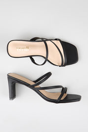 Model Genericm wearing size sample of the Ginny Heel - Black in colour Black, from an angle
