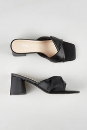 A model wearing size 37 of the Stella Block Heel Mule in colour Black (Black), from the front, showing the whole outfit