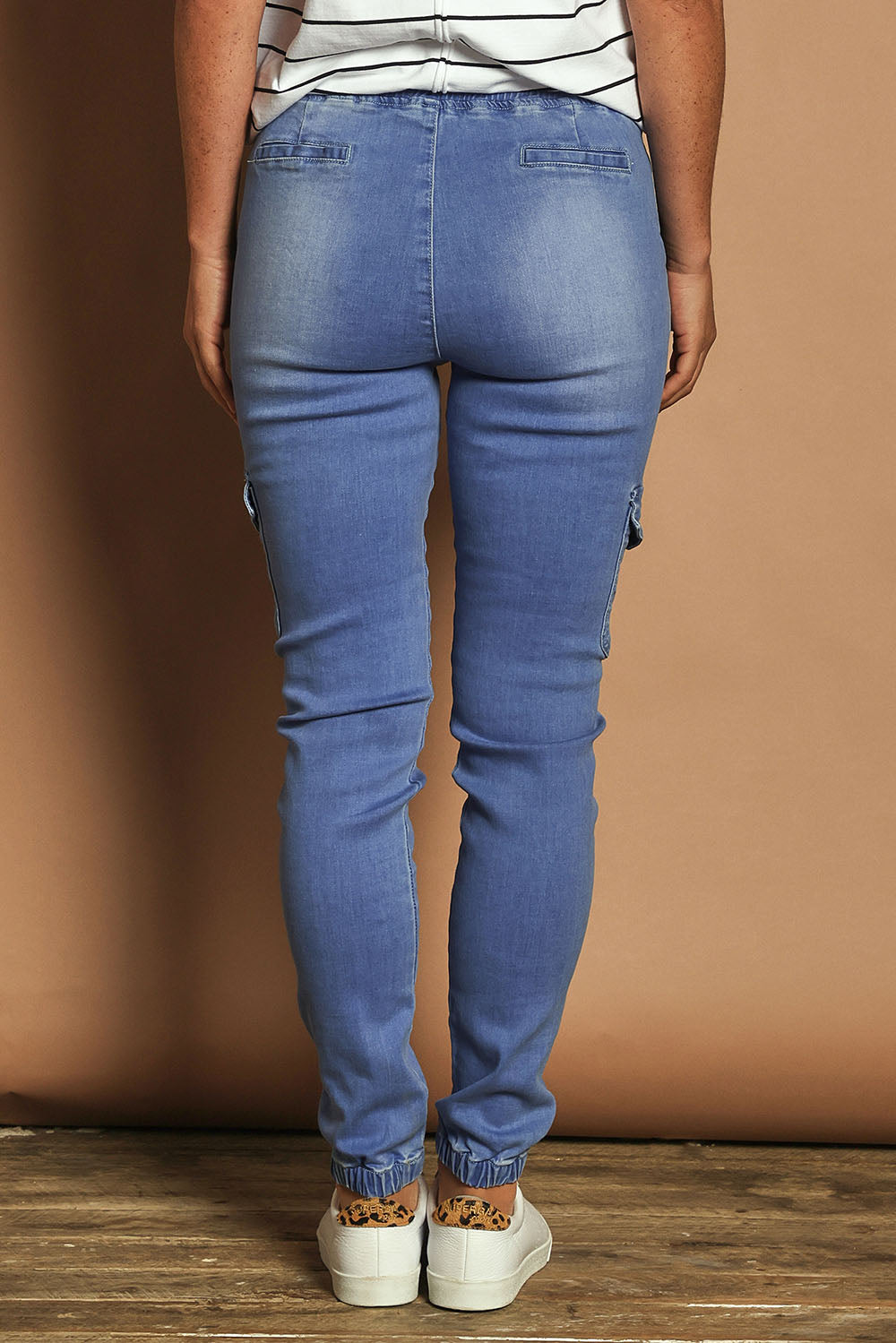 Model Katie wearing size 10 of the Harlow Cargo Jogger in colour Middenim (Blue), from the back