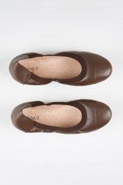 Model Genericm wearing size sample of the Ava Leather Flat - Chocolate in colour Chocolate, in a cropped view