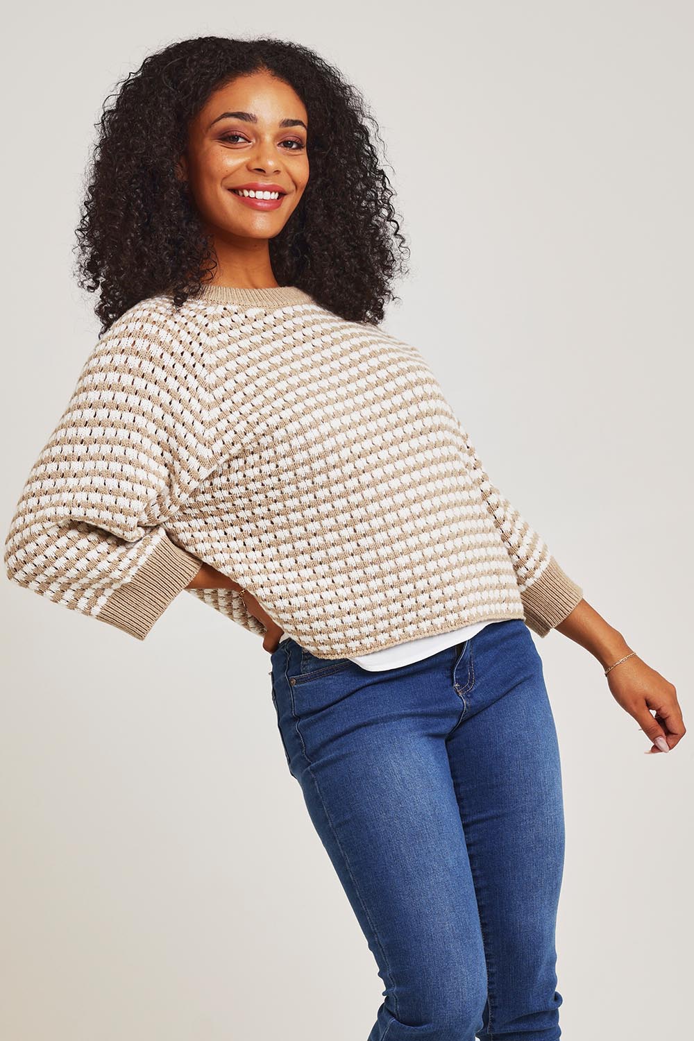Model Ziara wearing size S of the Texture Cotton Merino Jumper in colour Camel, from the front, cropped image